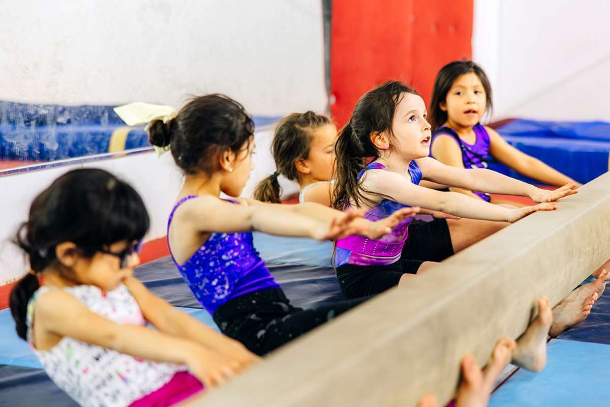 preschool gymnastics kids under bar, stretching their arms